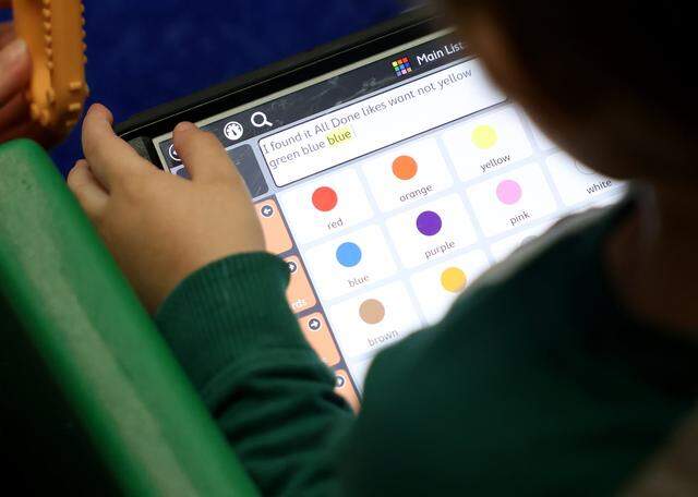 Phoenix, 3, uses an electronic device to help him communicate during circle at an early communication, language and social skills program at the Callier Center in Dallas on Thursday, March 5, 2026.